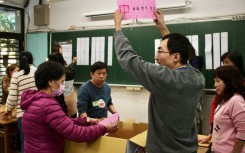 An official of a polling station holds up a ballot slip, as vote counting for the presidential elections commences, at a high school in New Taipei City on January 13, 2024. Vote counting got under way 