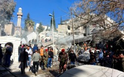 People and security forces gather in front of a building destroyed in a reported Israeli strike in Damascus on January 20