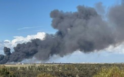 Smoke from bombardment billows in the background as displaced Palestinians flee Khan Yunis