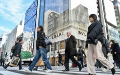 Pedestrians cross the street in front of luxury shops in the Ginza shopping district in Tokyo on January 19, 2024