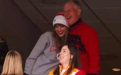Scott Swift (top R), seen taking in an American football game with daughter Taylor Swift (L), is accused of punching a photographer
