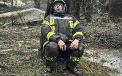 An injured rescuer leans next to a tree following a missile attack in Odesa