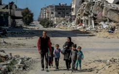 A Palestinian family walk past buildings destroyed in  Gaza City, where the UN has warned that famine is imminent without a major intervention