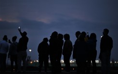 Onlookers watch in the distance the Francis Scott Key Bridge that collapsed in Baltimore, Maryland