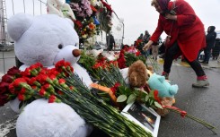 A woman lays flowers at a makeshift memorial to the victims in front of the Crocus City Hall outside Moscow