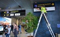 A Romanian worker changes the signs for passengers at Henri Coanda International Airport ahead of Romania and Bulgaria taking a first step into the Schengen visa free travel area on Sunday
