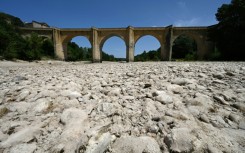 (FILES) A photograph shows the parched river bed of the Gardon near the Saint-Nicolas de Campagnac bridge in Saint-Anastasie, southern France, after a heat wave hit in June 2022