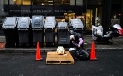 A woman searches through a trash bag in Manhattan on March 20, 2024