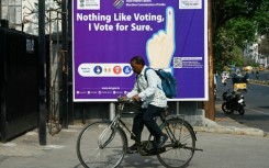 A man rides past an election awareness poster displayed on a street ahead of India’s upcoming general elections, in Hyderabad 