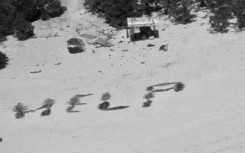 The 'HELP' sign made with palm fronds by three mariners stranded on a remote island in Micronesia is seen in an image obtained from the US Coast Guard