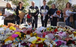 Australian Prime Minister Anthony Albanese (C, with NSW premier Chris Minns) leave flowers in tribute to the victims of the shopping mall attack