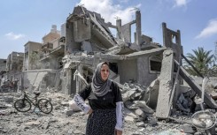 A woman stands amid rubble in the Maghazi camp for Palestinian refugees in the central Gaza Strip on April 15, 2024