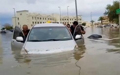 Residents push a waterlogged car along a flooded street in the desert city of Dubai after torrential rains paralysed the Gulf financial and leisure hub