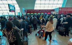 Passengers queue at a flight connection desk at Dubai airport