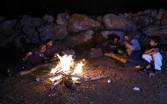 Palestinian men sit around a camp fire as they watch over livestock amid settler attacks in the West Bank