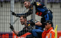 Red Bull team members celebrate on the pit wall as Max Verstappen wins