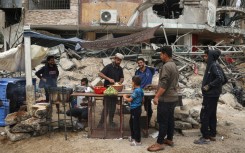 A Palestinian vendor prepares to make falafel sandwiches on a makeshift stall next to the rubble of a destroyed building in Khan Yunis in the southern Gaza Strip