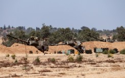 Israeli troops man a position with mobile artillery units in southern Israel near the border with the Gaza Strip
