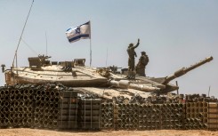 An Israeli army soldier gestures atop the turret of a main battle tank in southern Israel near the Gaza border 