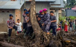 Rescue teams and people move logs that had washed into residential areas in western Indonesia