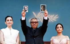 Mohammad Rasoulof of Iran held pictures of his actors on the red carpet