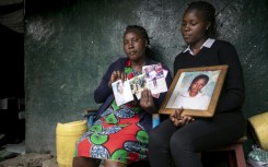 Rose Wanjiku (left) and another relative look through photographs of her sister Agnes who was killed in 2012 