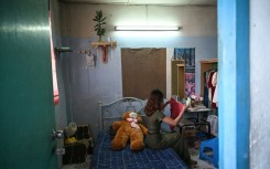 "Khaing", a former teacher, beside a large teddy bear gifted to her by a friend who knew she was feeling lonely