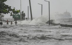 Youngster frollick in a storm surge along Manila Bay during heavy rain brought by Tropical Storm Yagi