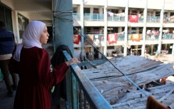 A displaced Palestinian stares from a balcony at a bombarded school-turned-shelter in northern Gaza