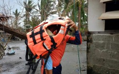 A rescuer carries a young resident during a forced evacuation operation in the northern Philippines ahead of Typhoon Usagi's landfall