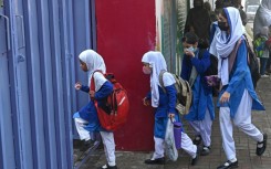 Students wearing masks arrive for classes as schools reopened amid smoggy conditions in Lahore on Wednesday