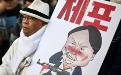 A man carrying a placard with a comic depicting South Korea's impeached president Yoon Suk Yeol