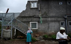 Local residents whose homes have been destroyed by the Chido cyclone stand in front of a damaged building in the village of Sohoa, on the French Indian Ocean territory of Mayotte