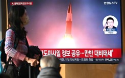 People watch a television screen showing a news broadcast with file footage of a North Korean missile test, at a train station in Seoul