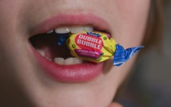 A boy holds a wrapped Dubble Bubble Bubble Gum candy in his mouth, a product that uses Red Dye No 3, in this illustration photograph on December 27, 2024
