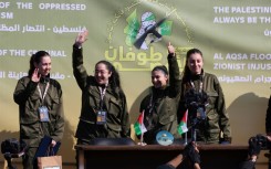 Four Israeli hostages wave on a stage before Hamas fighters hand them over to a team from the Red Cross in Gaza City