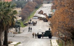 Lebanese army soldiers (R) and Israeli troops gather near their vehicles on either side of a barbed wire barrier, as an Israeli bulldozer pours soil to build a roadblock in Borj al-Mlouk in the border district of Marjayoun, southern Lebanon
