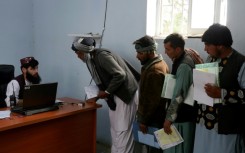 Afghan men stand in queue to submit their documents as they apply for passport in Herat