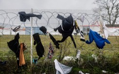 Drenched clothes hang on a barbed wire fence nearby