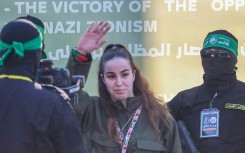 Israeli woman soldier Agam Berger waves as Hamas militants escort her onto a stage for her handover to Red Cross representatives as part of the third hostage-prisoner exchange of the Gaza ceasefire.