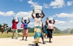 Mothers carry boxes of porridge backed by US aid in the Mutokoarea of Zimbabwe in 2019 as drought worsened hunger
