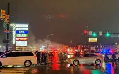 A plume of smoke and emergency responders can be seen after a small aircraft crashed in a neighborhood in Philadephia, Pennsylvania on January 31, 2025