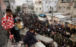 Children look on as Hamas fighters and mourners perform the noon prayer during the funeral for top Hamas commander Marwan Issa in central Gaza's Bureij refugee camp