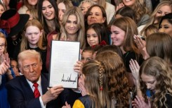 US President Donald Trump holds up a newly signed executive order that seeks to ban transgender female athletes from participating in women's sports