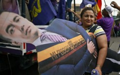A supporter carries a life-size cardboard cutout of Ecuador's President and presidential candidate Daniel Noboa at a campaign rally