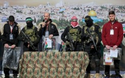 Hostages (L to R) Sagui Dekel-Chen, Yair Horn and Sasha Trupanov stand on stage next to Palestinian militants during their release
