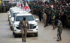 A Palestinian Hamas fighter precedes International Red Cross vehicles as they arrive in the central Gaza Strip to receive three Israeli hostages. Israeli Prime Minister Benjamin Netanyahu has described the described the ceremonies as "humiliating"