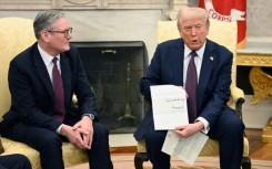 Donald Trump holds a letter from Britain's King Charles III during a bilateral meeting with British Prime Minister Keir Starmer in the Oval Office 