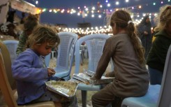 Palestinian children eat their food during a group Iftar meal, the evening meal with which Muslims end their daily fast at sunset, in Gaza City 