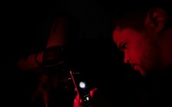 A man photographs the 'blood moon' with his phone through a telescope in Belo Horizonte, Brazil on March 14, 2025